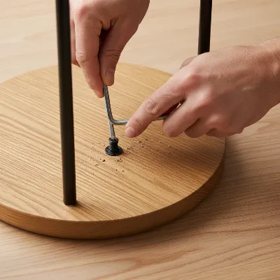 A person tightening screws on a bar stool leg with an Allen key, focused on DIY repair.