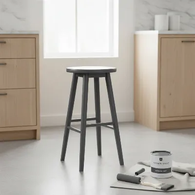 A beautifully painted wooden bar stool with painting tools nearby, showcasing a smooth, refreshed finish.