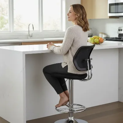 A person testing the comfort of an ergonomic bar stool, focusing on lumbar support and footrest.